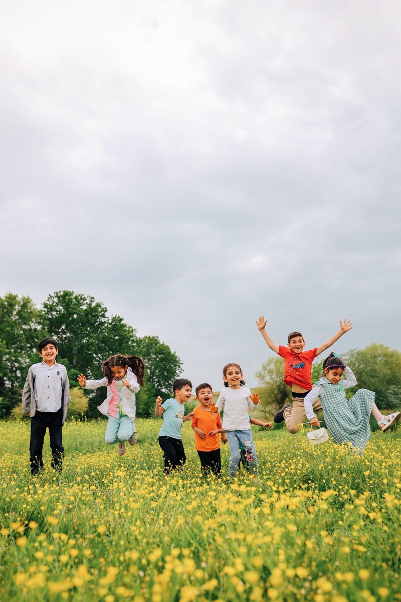 Kinder springen ausgelassen über eine Blumenwiese