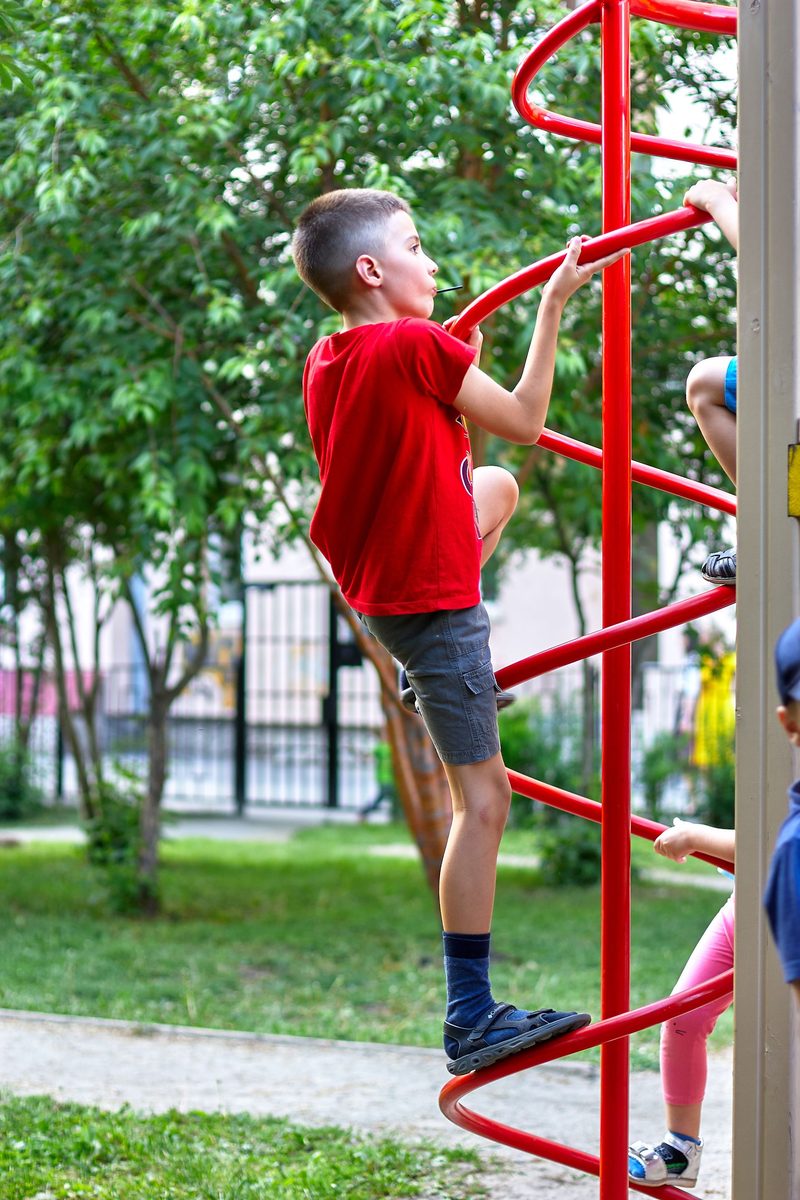 Kind klettert an einem Spielgerät