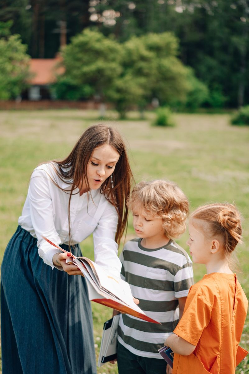 Erzieherin liest Kindern im Freien vor
